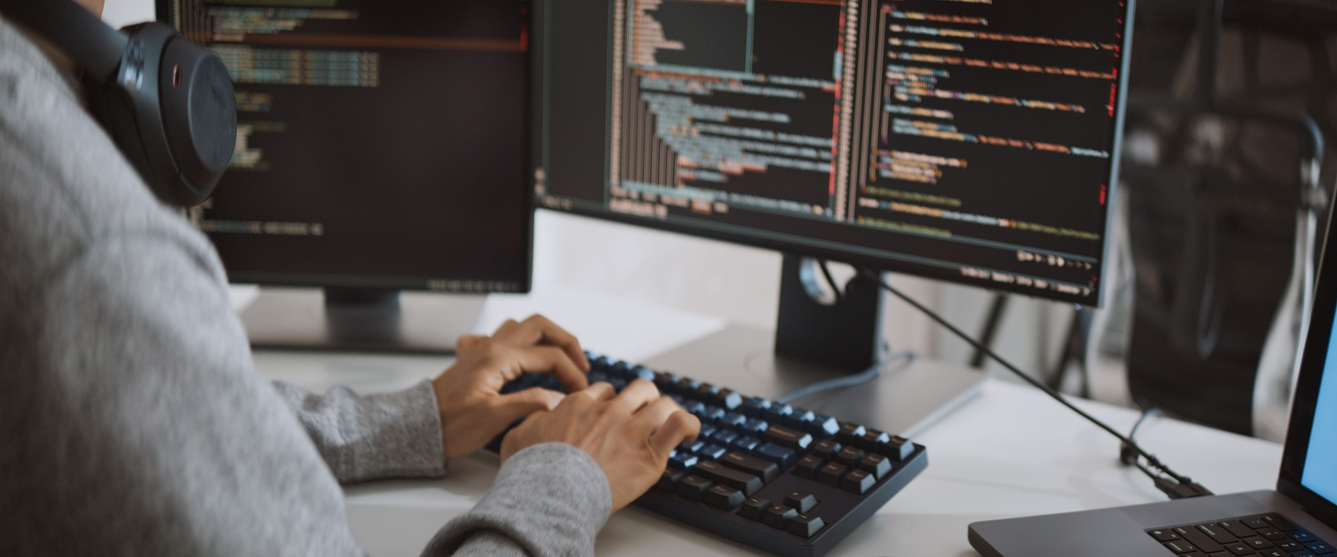 Young adult Asian male software developer coding program on desktop computer. Man work from home, remote working, freelance programmer job, smart digital nomad lifestyle concept. Close Up